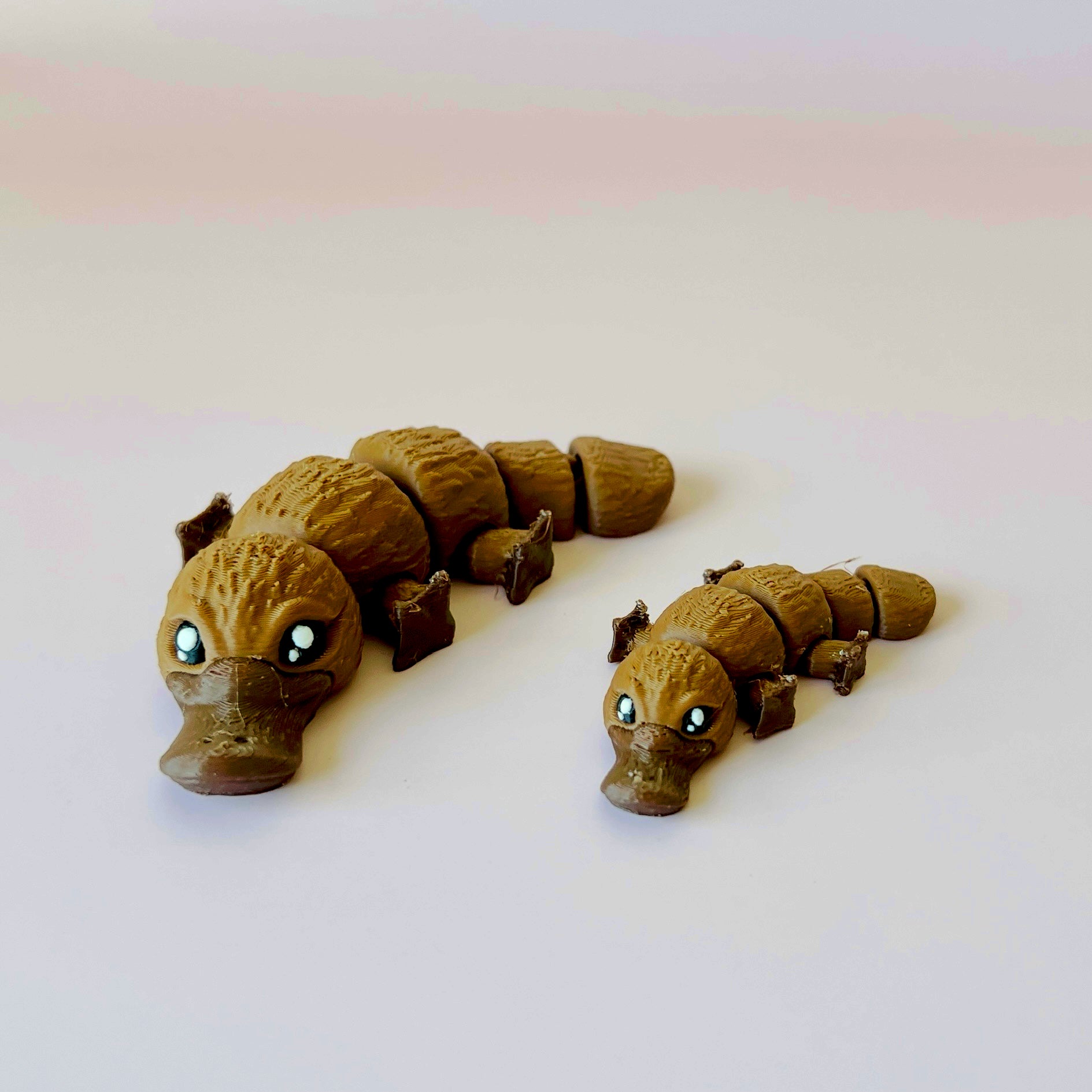 Two whimsical, stylized creatures with large eyes, one larger than the other, on a plain background.