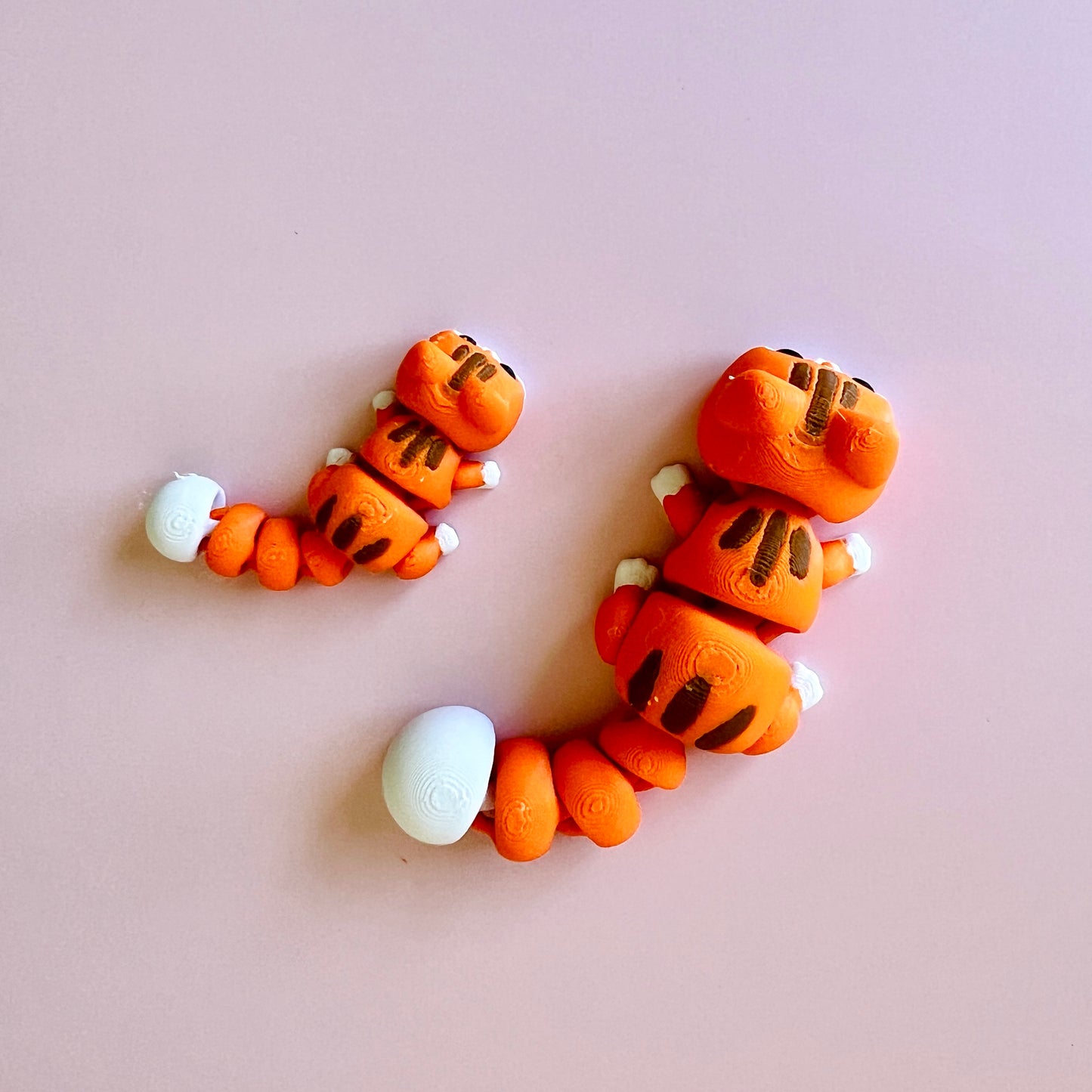 Two playful orange creatures with white accents, posed on a soft pink background.