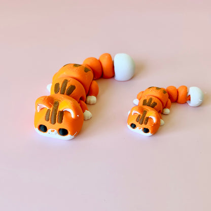 Two orange, segmented creatures with cat-like features, sitting on a soft pink background.