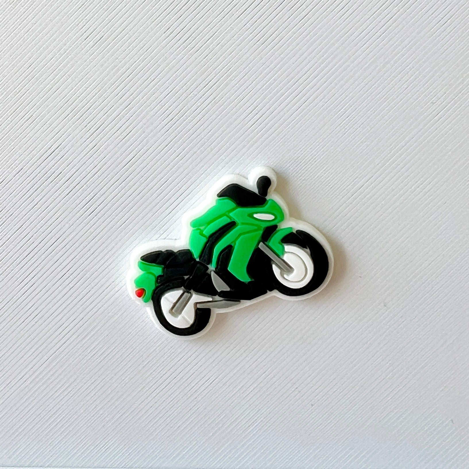 A vibrant green motorcycle with black accents, set against a textured white background.