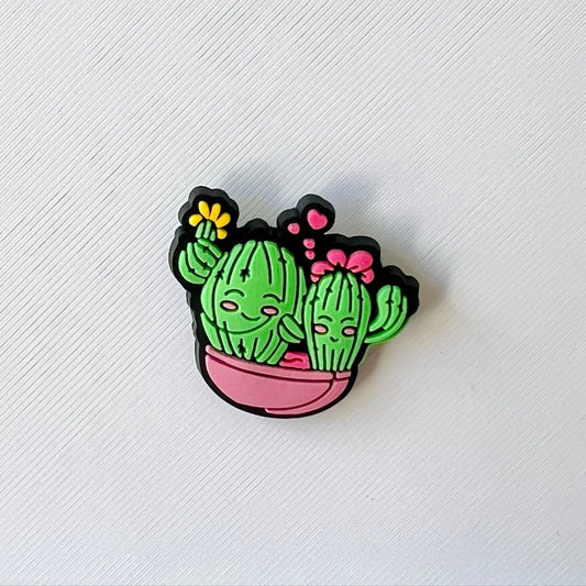Colorful cactus characters with smiling faces, adorned with flowers, in a pink pot against a textured white background.