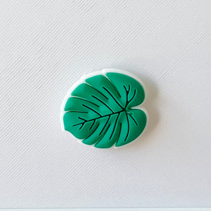 A green leaf shape with intricate vein details, set against a textured white background.