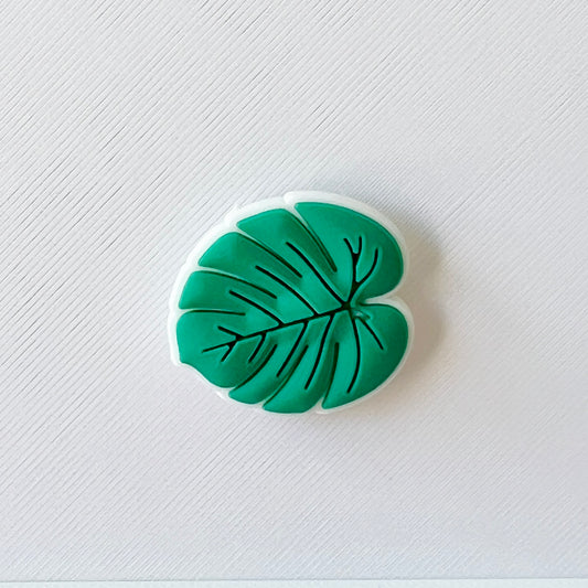 A green leaf shape with intricate vein details, set against a textured white background.