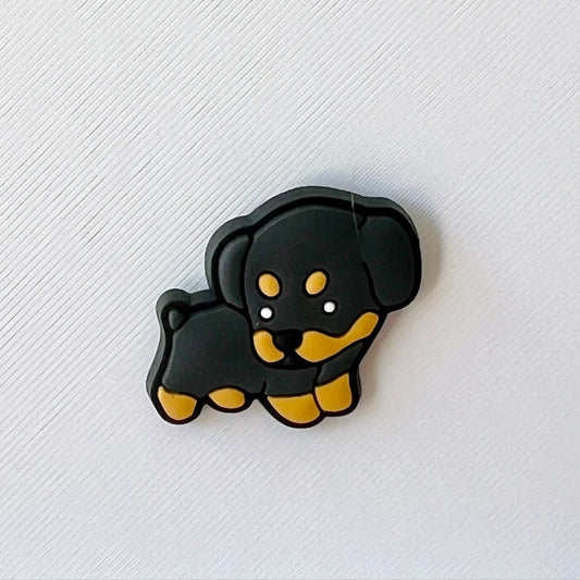 A playful black and tan puppy with a cheerful expression, set against a textured white background.