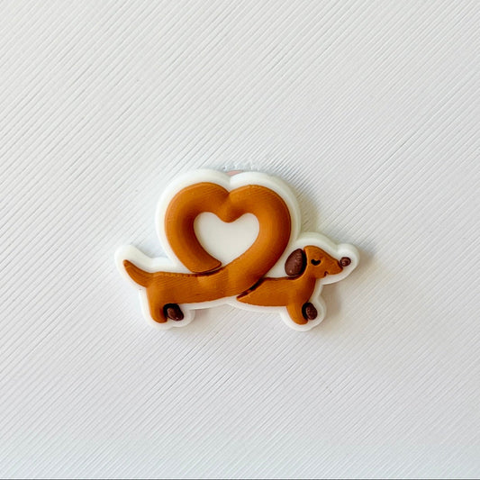 A cute brown dachshund playfully forms a heart shape with its body against a textured white background.