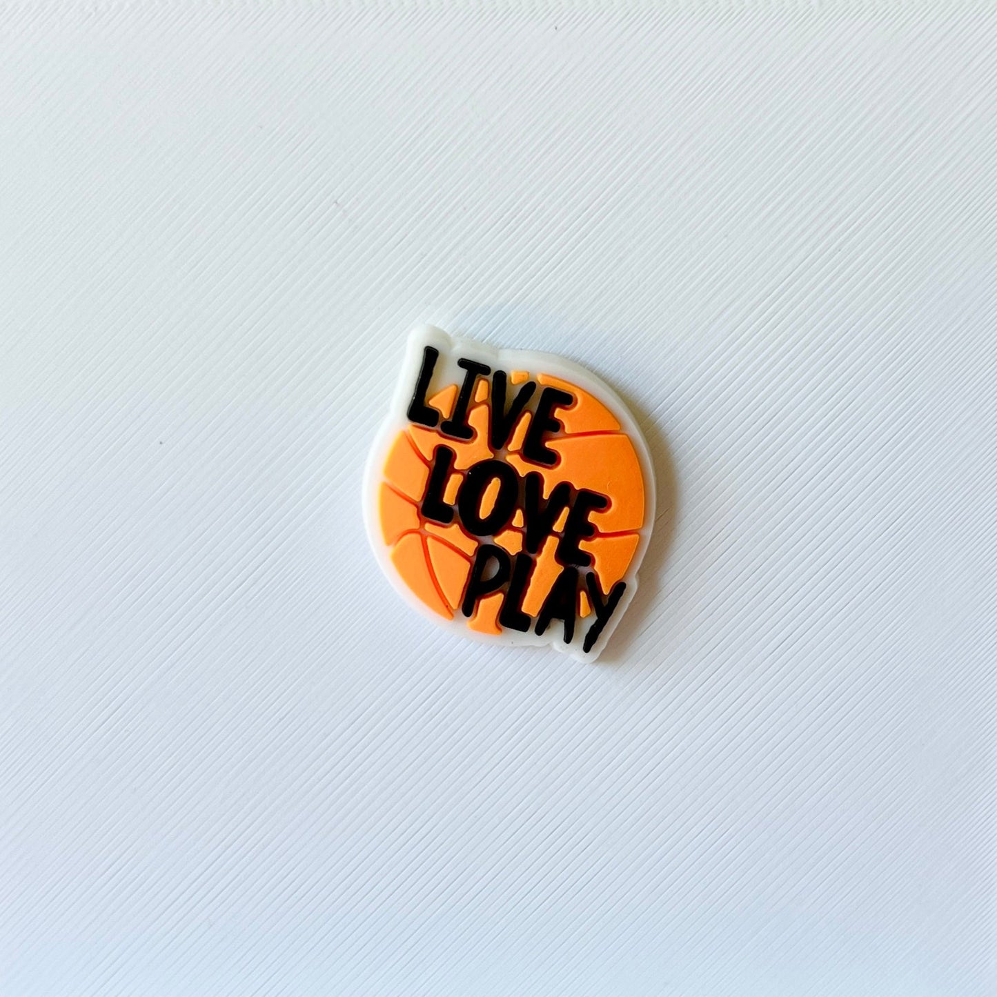 A round, orange piece featuring the phrase "LIVE LOVE PLAY" in bold black letters against a textured white background.