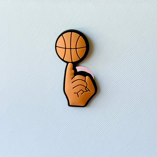 A hand holding a basketball on a finger, showcasing a playful and dynamic gesture against a textured background.