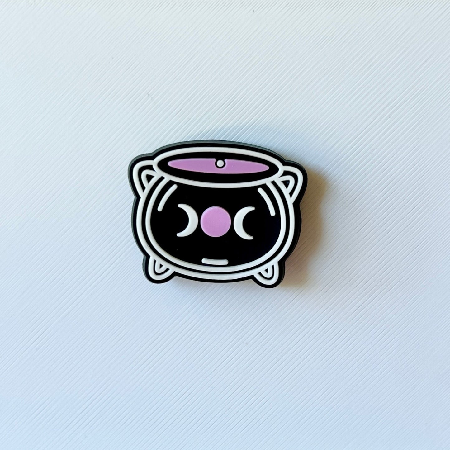 A cute, black cat-shaped container with pink accents and a whimsical face, set against a textured white background.