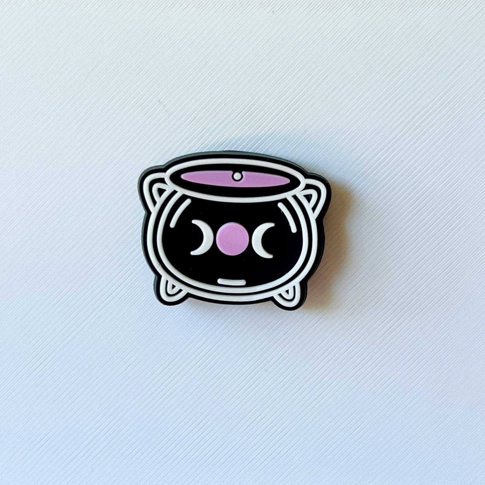 A cute, black cat-shaped container with pink accents and a whimsical face, set against a textured white background.