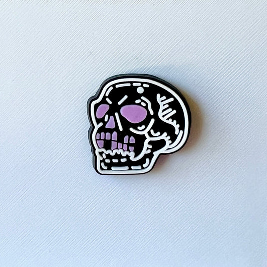 A stylized skull with a black outline and lavender accents against a textured white background.