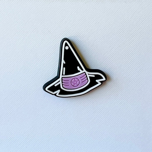A black witch's hat with a purple band and pentagram detail, set against a textured white background.