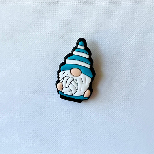 A whimsical gnome figure with a blue and white striped hat, holding a ball of yarn, set against a textured white background.