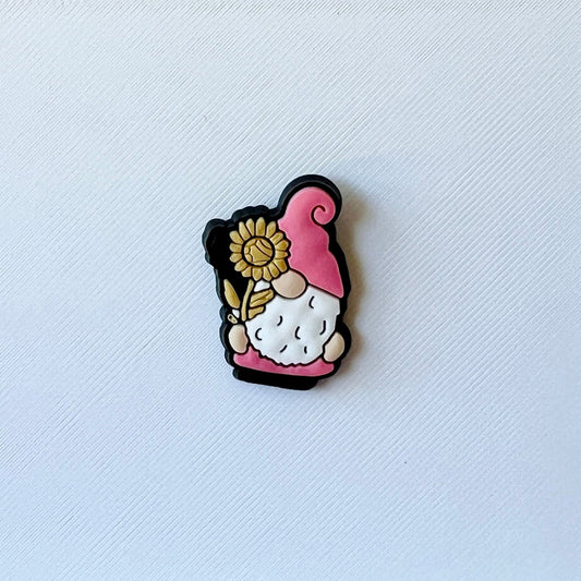 A whimsical gnome figure with a pink hat and sunflower, set against a textured white background.