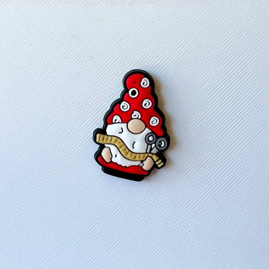 A whimsical figure with a red hat adorned with spirals, holding a tool and a measuring tape, set against a textured white bac
