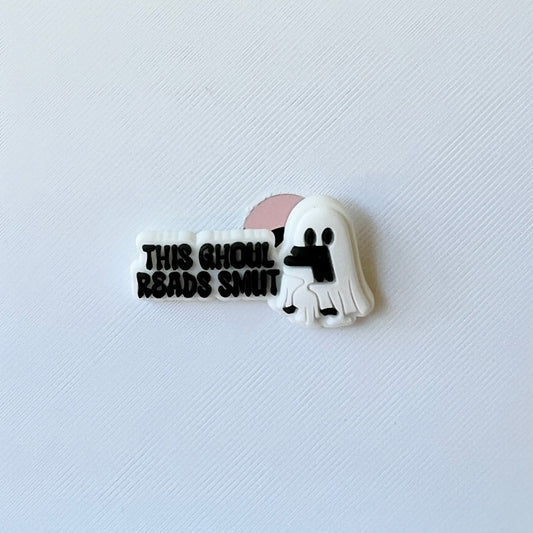 A playful ghost character holding a book, accompanied by the text "THIS GHOUL READS SMUT" in bold lettering.