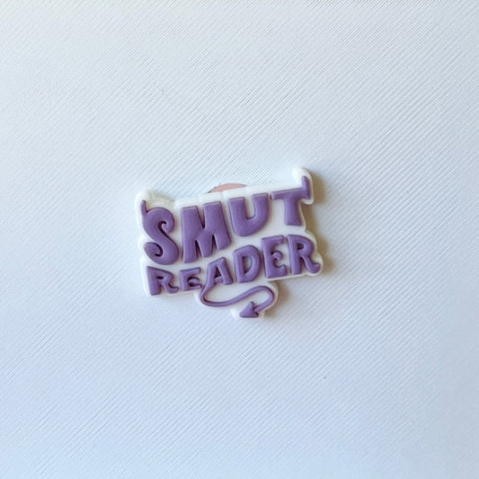 A playful purple and white badge with "SMUT READER" in bold, whimsical font against a textured white background.