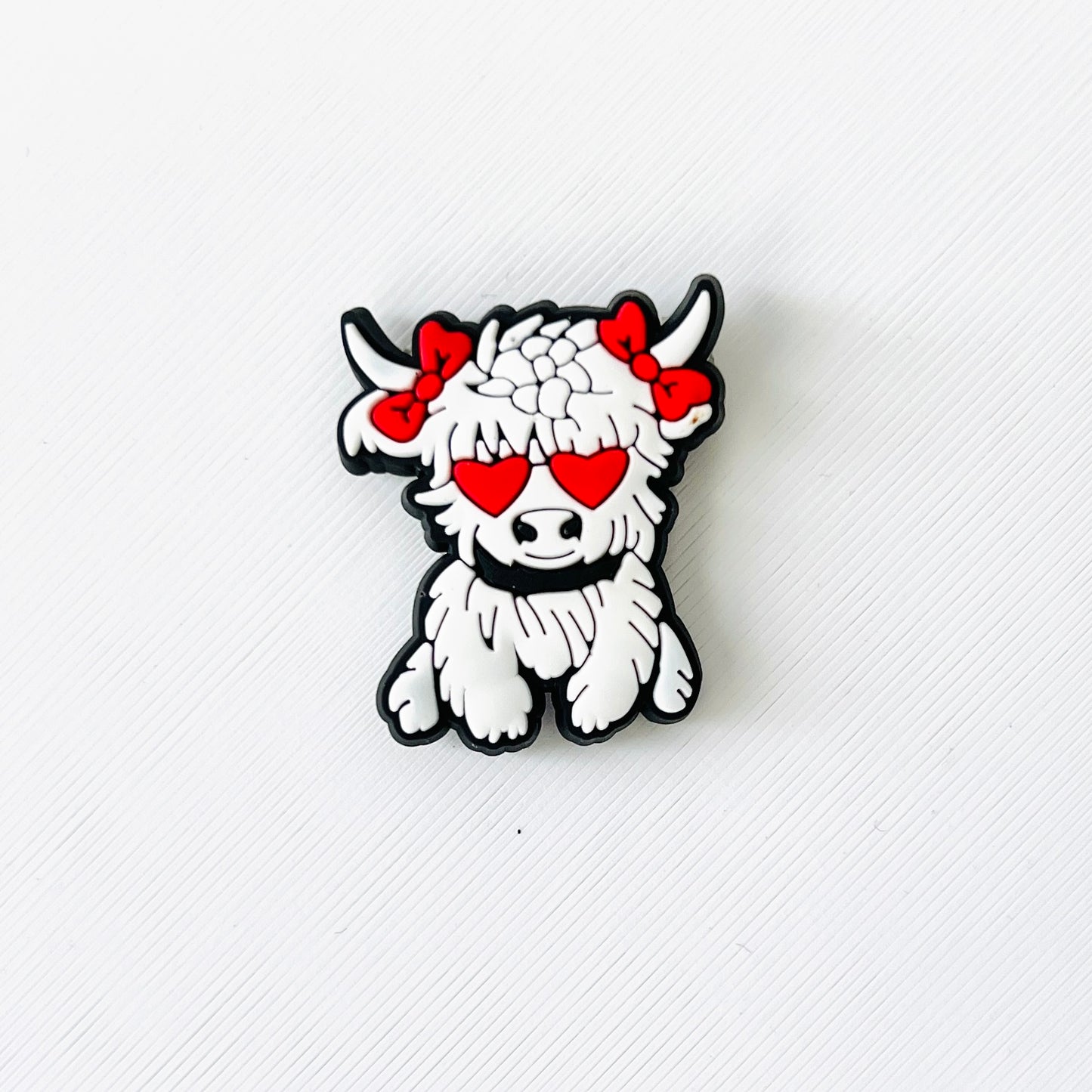 White Highland cow charm with red heart eyes and bows, adding a playful touch to shoes for animal lovers and romantics.