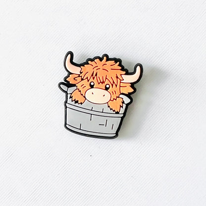 Adorable Highland cow with fluffy orange fur peeking out of a rustic tub, perfect for adding charm to your footwear.