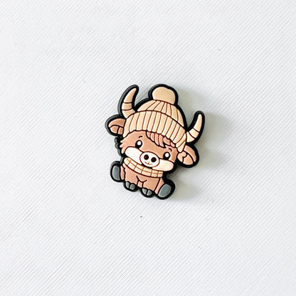 Adorable Highland cow wearing a cozy beanie and scarf, perfect for adding winter charm to your favorite shoes.