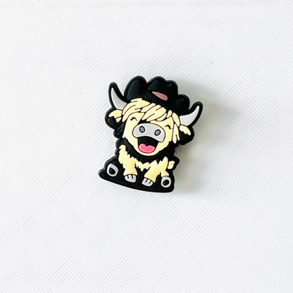Fluffy Highland cow charm wearing a cowboy hat, featuring a cheerful expression and fun Western flair.