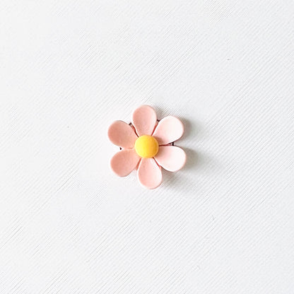 Light pink flower charm with soft petals and a bright yellow center, set against a white background. Perfect for shoes!