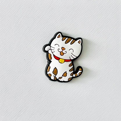 White and brown cat charm with a red collar, playful expression, and paw raised, perfect for adding cuteness to shoes.