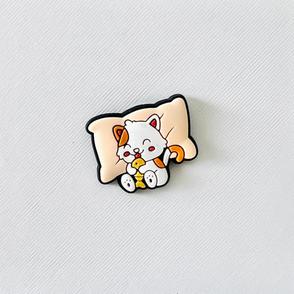 Adorable sleepy cat resting on a pillow, joyfully holding a fish snack, perfect for cozy shoe charm lovers.