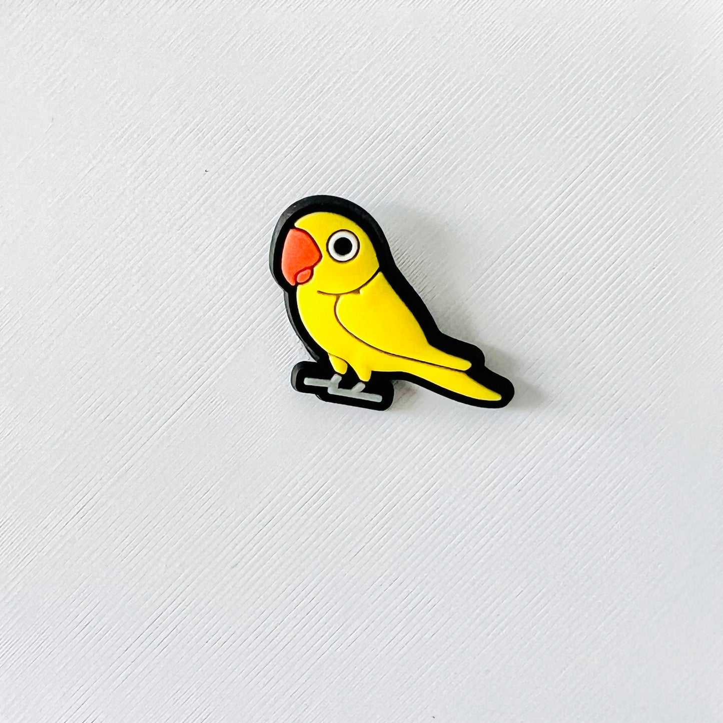 Cheerful yellow parrot charm with black outline, perfect for brightening shoes and showcasing a love for vibrant accessories.