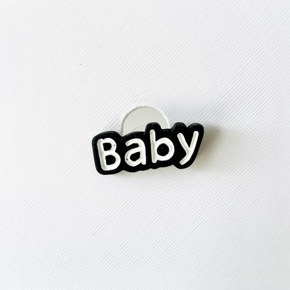 "Playful 'Baby' charm in bold white lettering with a black outline, perfect for adding style to your shoes."