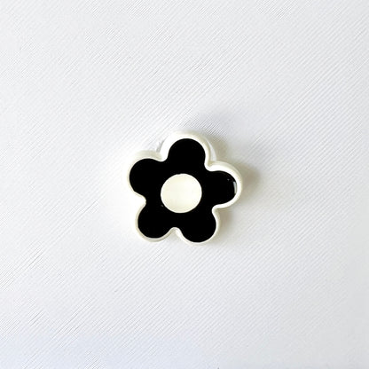 Chic black and white flower charm features a glossy finish, perfect for adding elegance to shoes with a classic touch.
