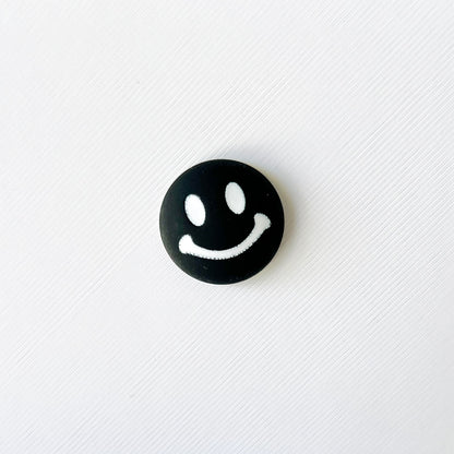 Black and white charm featuring a smiling face with bright eyes, perfect for adding cheerful vibes to footwear.