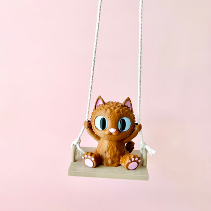 Adorable 3D-printed cat with big eyes happily swinging, showcasing charming details and tiny paws on a pastel background.