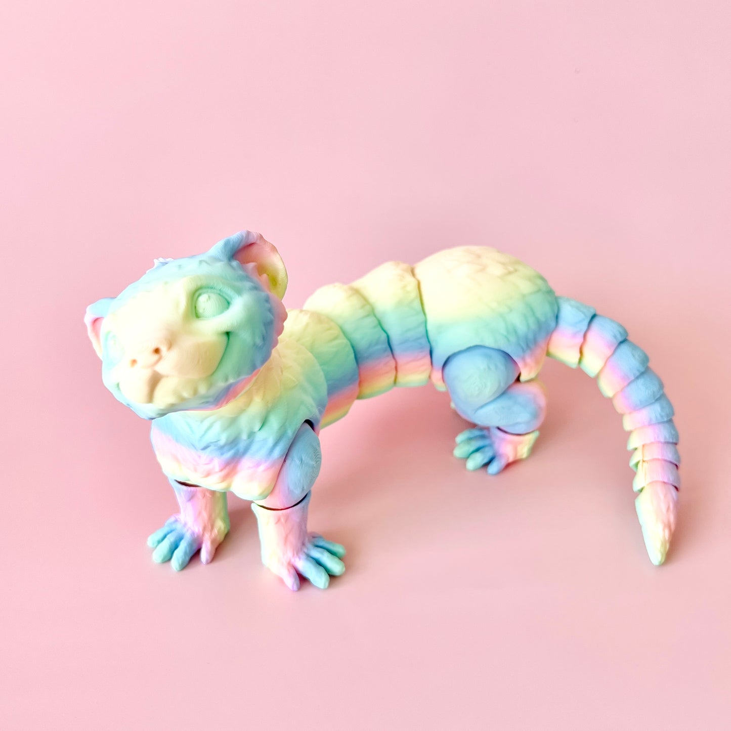 Colorful 3D-printed ferret figurine with intricate details, posing playfully against a pink background.