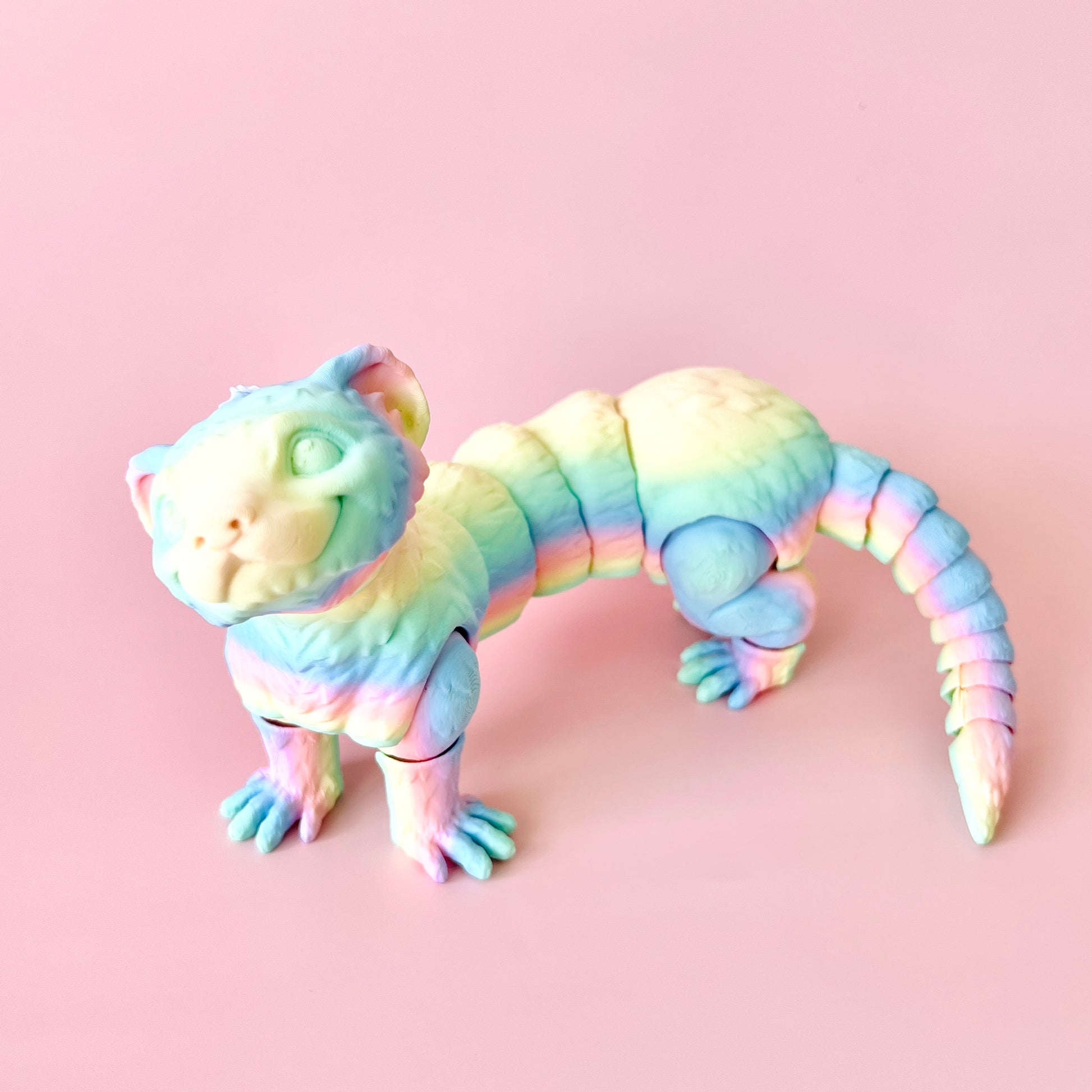 Colorful 3D-printed ferret figurine with intricate details, posing playfully against a pink background.