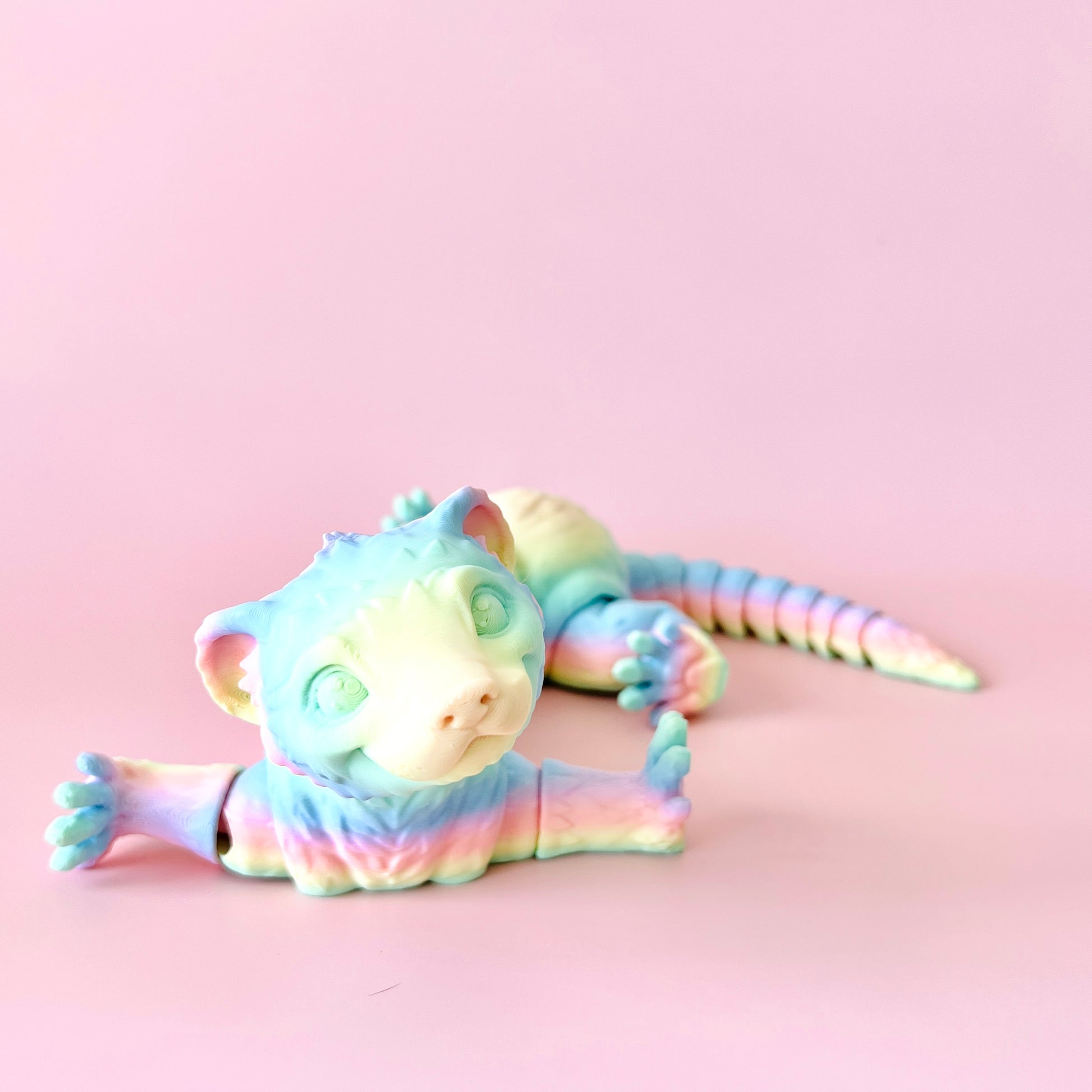 Colorful 3D-printed ferret figurine with intricate details, showcasing playful charm against a soft pink background.