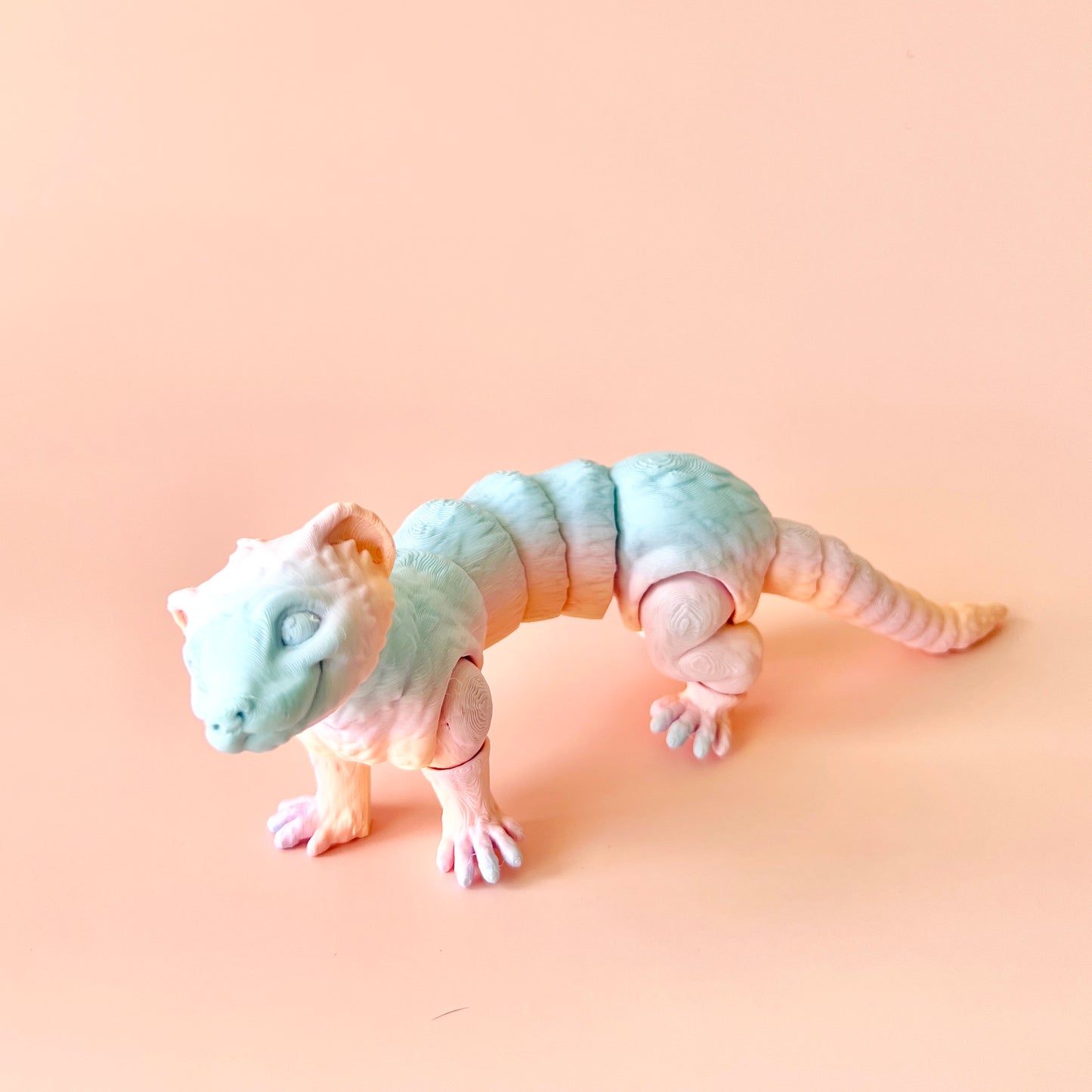 3D-printed ferret figurine with intricate details, featuring customizable colors on a soft pink background.