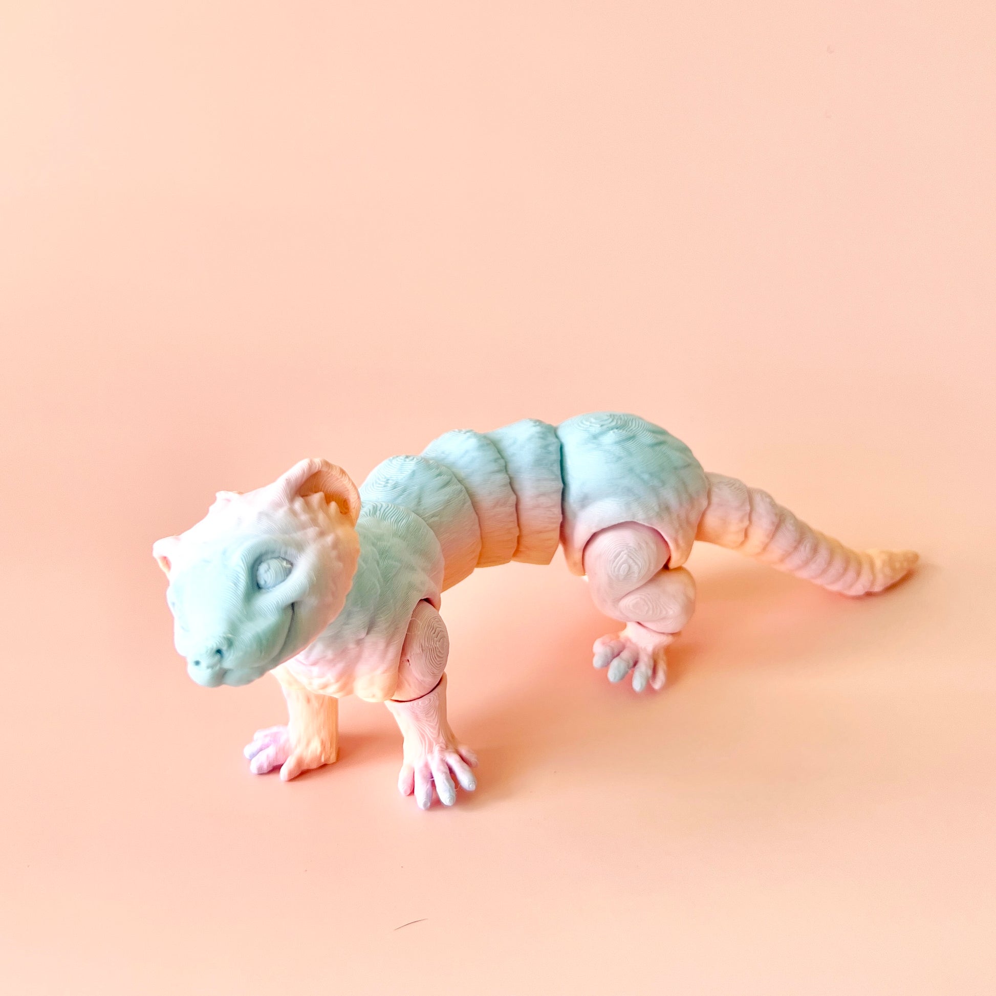 3D-printed ferret figurine with intricate details, featuring customizable colors on a soft pink background.