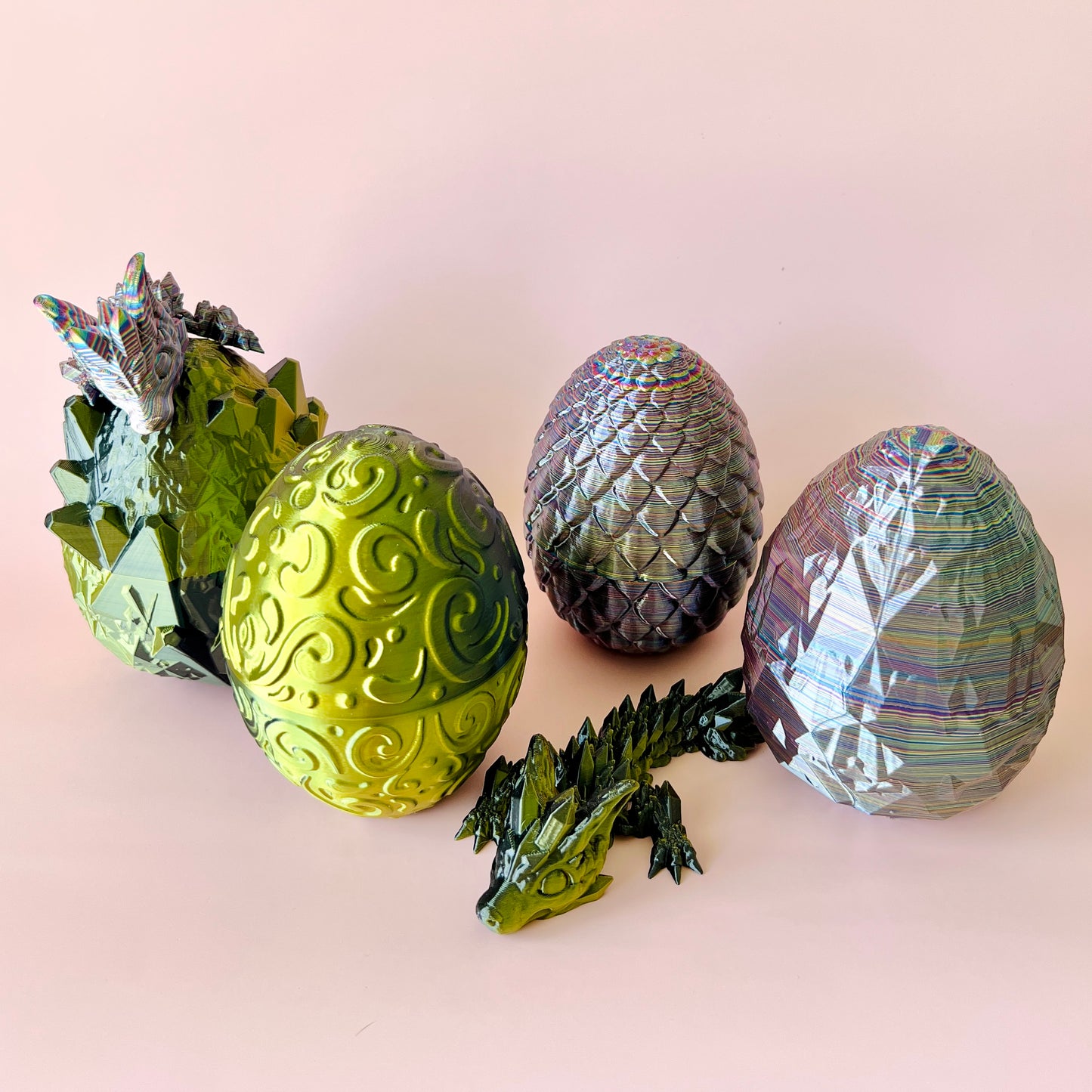 A vibrant green dragon and four colorful, textured eggs in various styles against a soft pink background.