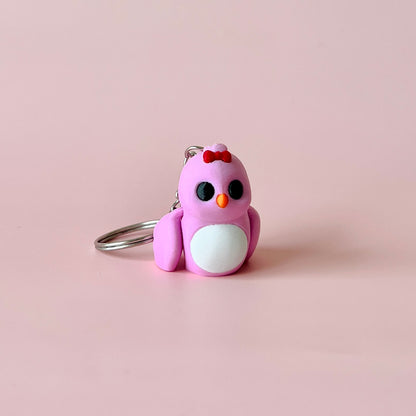 A small, pink bird figure with a red bow, black eyes, and white belly, resting on a soft pink background.