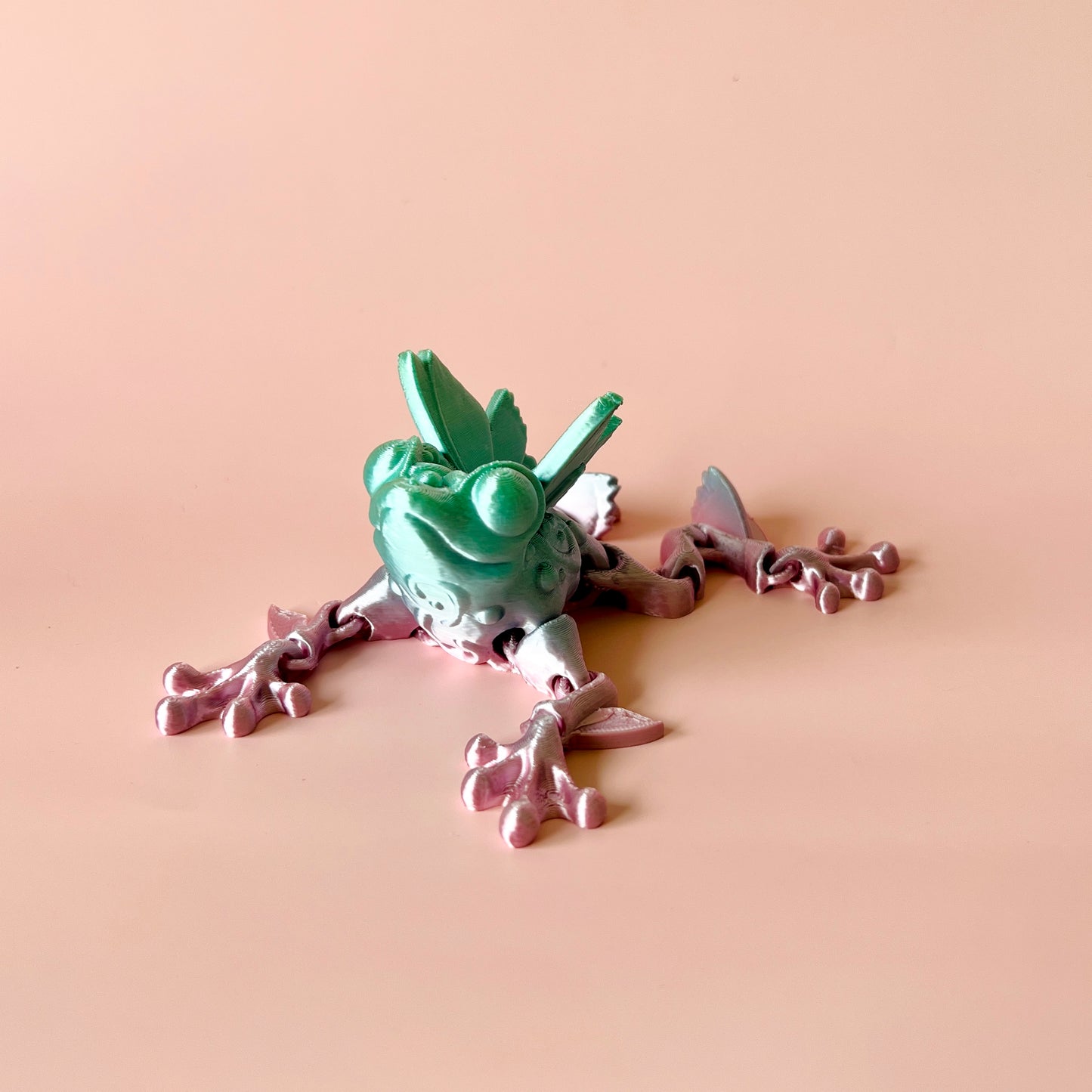 Whimsical frog with butterfly-inspired details in green and pink, perfect for display or playful interaction.