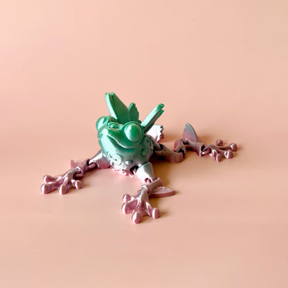 Whimsical frog with butterfly-inspired details in green and pink, perfect for display or playful interaction.