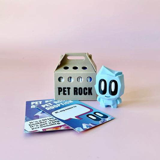 A pastel blue figure with big eyes next to a light brown carrying box and colorful adoption cards on a pink background.