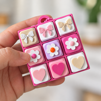 9 Key Fidget Clicker Square, 3D printed fidget clicker in pink with bow, daisy and heart keycaps, held in hand