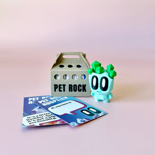 A playful, pastel green character with crystal-like features beside a pet rock adoption box and colorful cards.
