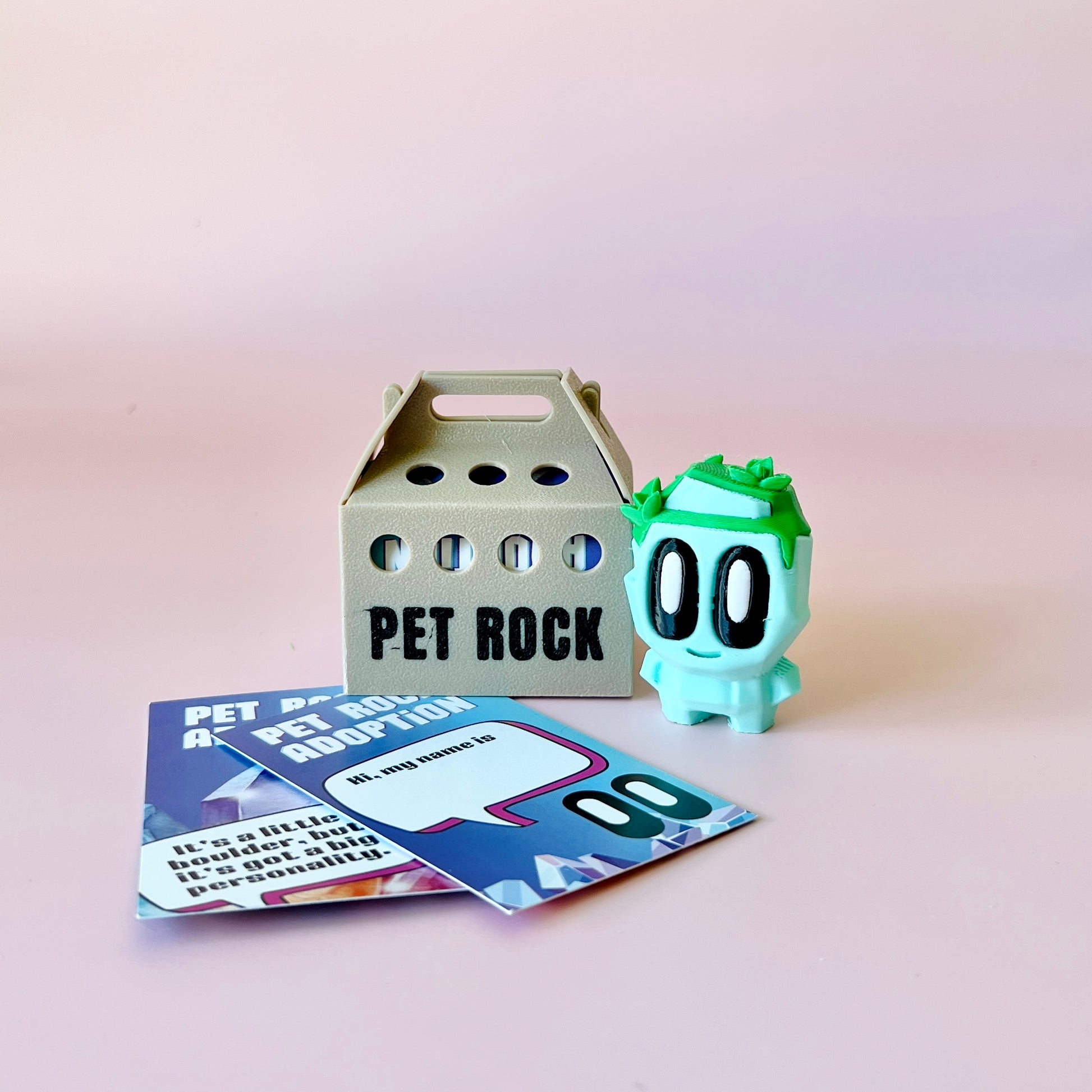 A whimsical green character with large eyes beside a gray carrier and colorful adoption cards on a pink background.