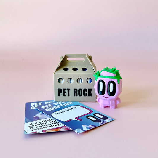A playful pink figure with eyes and green accents beside a small carrier and adoption cards on a soft pink background.