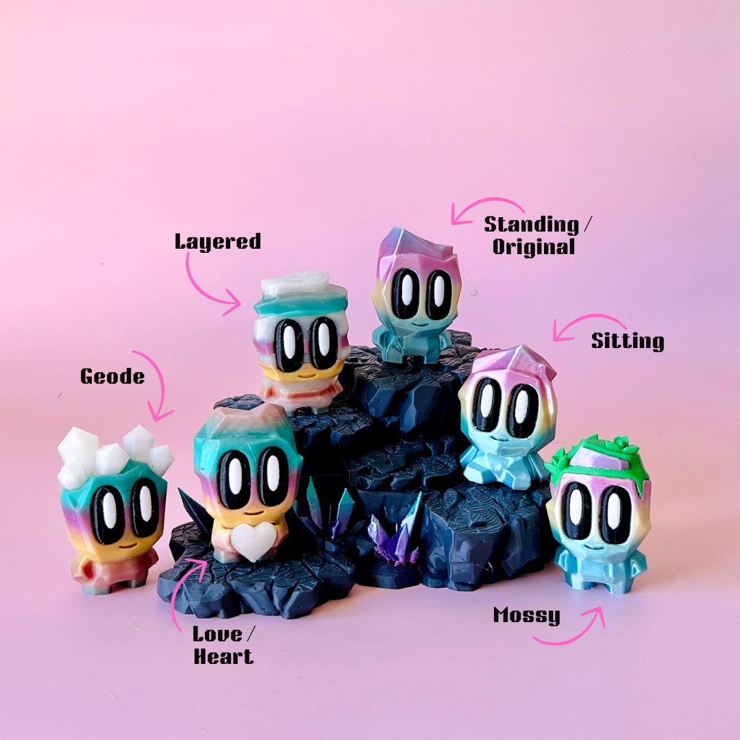 Colorful characters with oversized eyes stand on a rocky base, surrounded by sparkling gems against a pink backdrop.