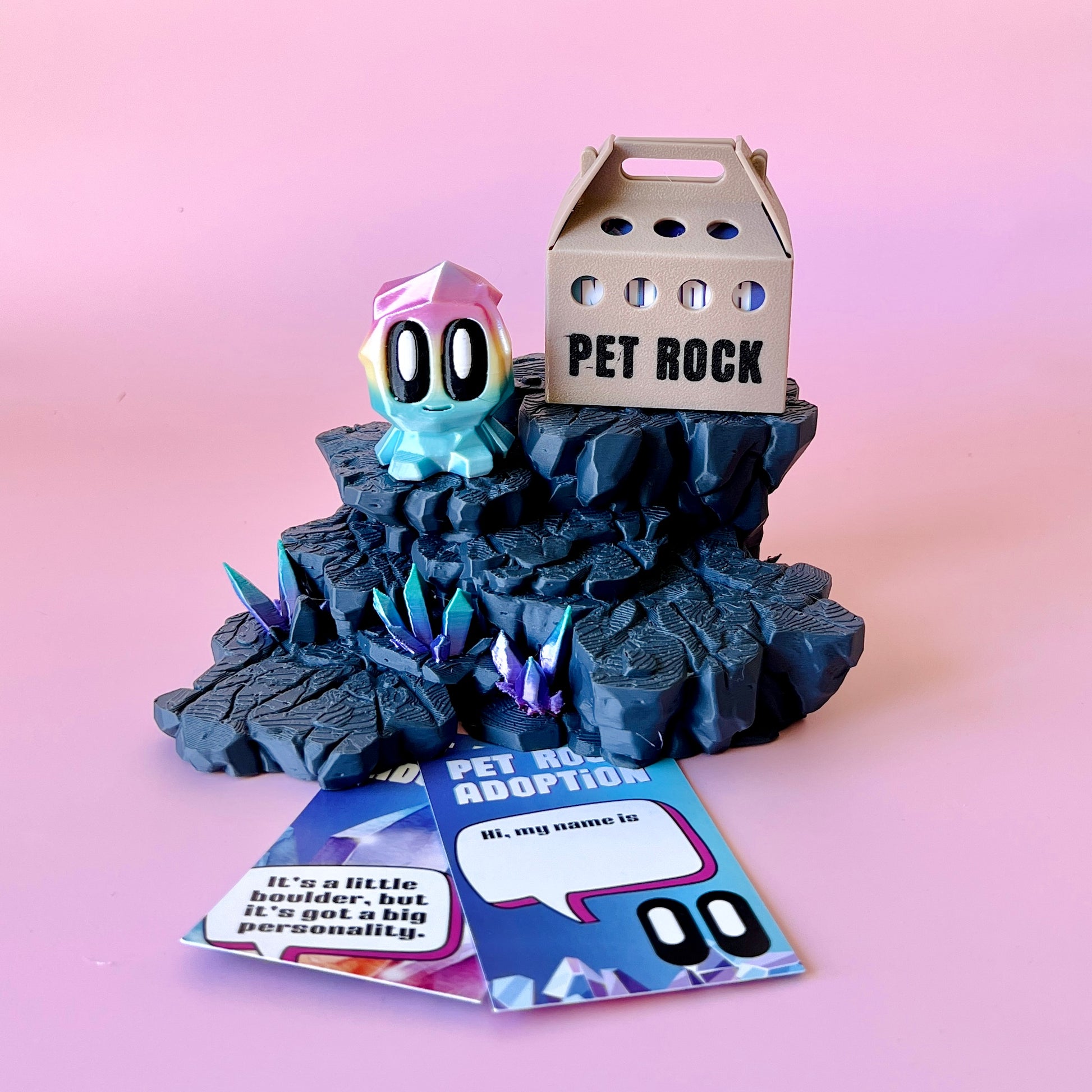 A colorful, whimsical creature perched on a rocky base with sparkling crystals, alongside a playful adoption card.