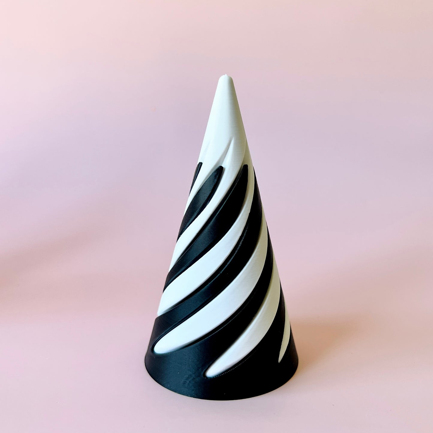A spiraled cone with alternating black and white sections against a soft pink background.