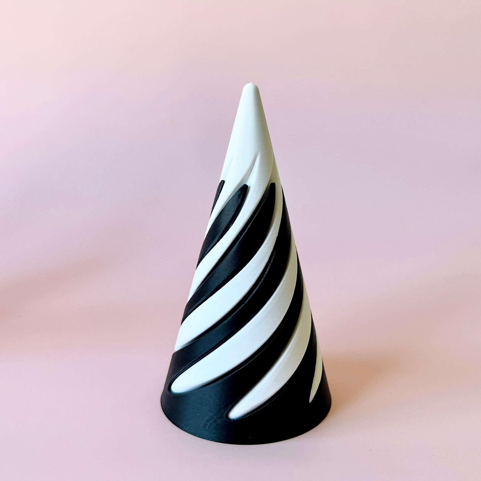 A spiraled cone with alternating black and white sections against a soft pink background.